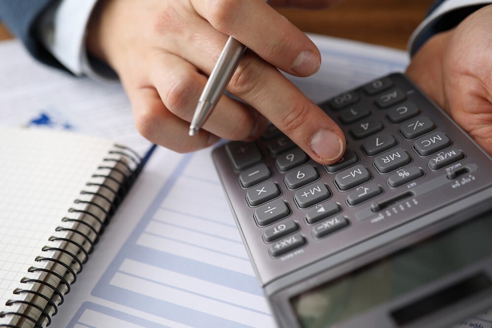 Man typing on calculator to find how much homeowner's insurance costs
